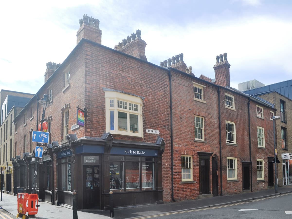Row of small three-storey brick houses on a street corner.