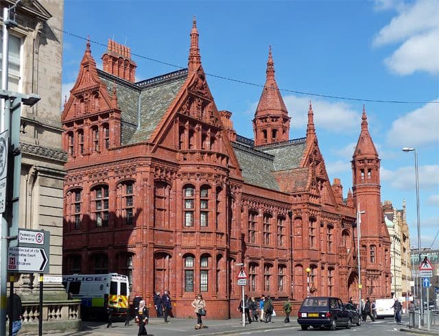 An ornate red terracotta Victorian law court with a central gabled entrance and towers.