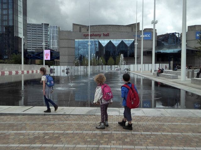 A large modern concert hall building facing a paved public square.