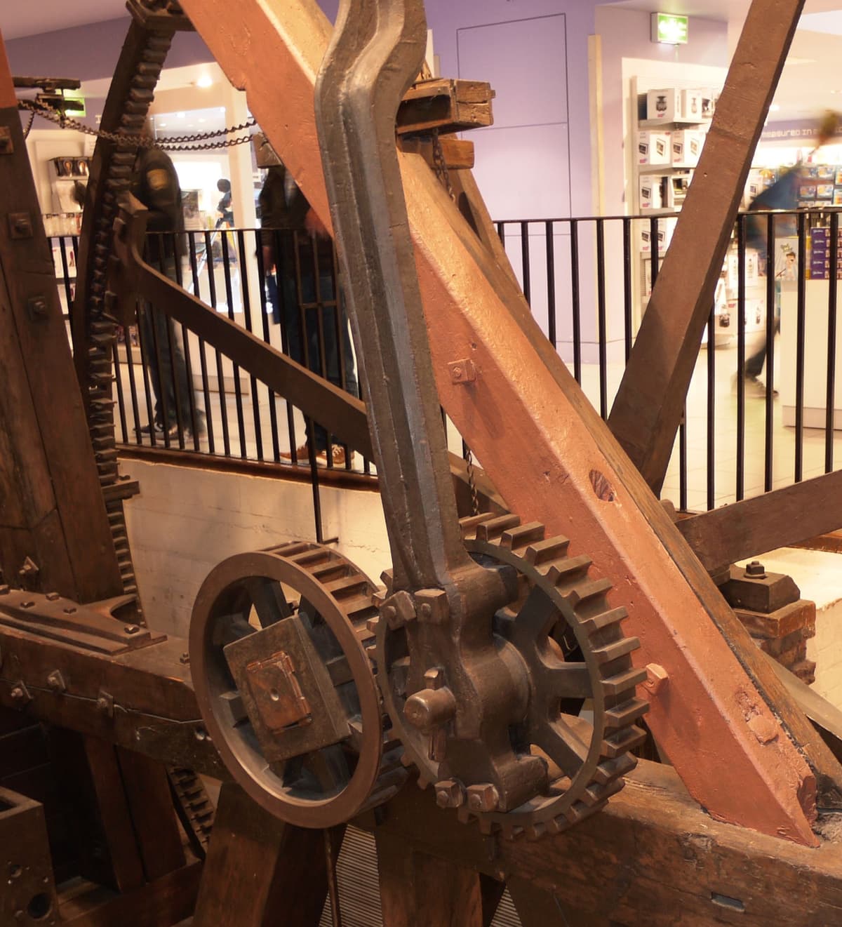 Close view of an old timber and iron beam engine: a toothed ‘planet’ wheel fixed to the end of the connecting rod meshes with a toothed ‘sun’ wheel on the flywheel shaft.