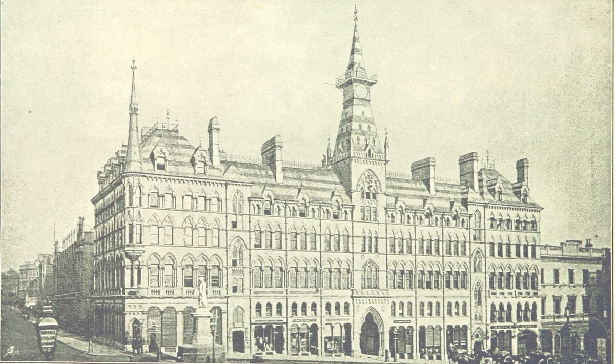 Engraving of a large Gothic stone building on a street corner with a central clock tower and spire, and a statue in front.