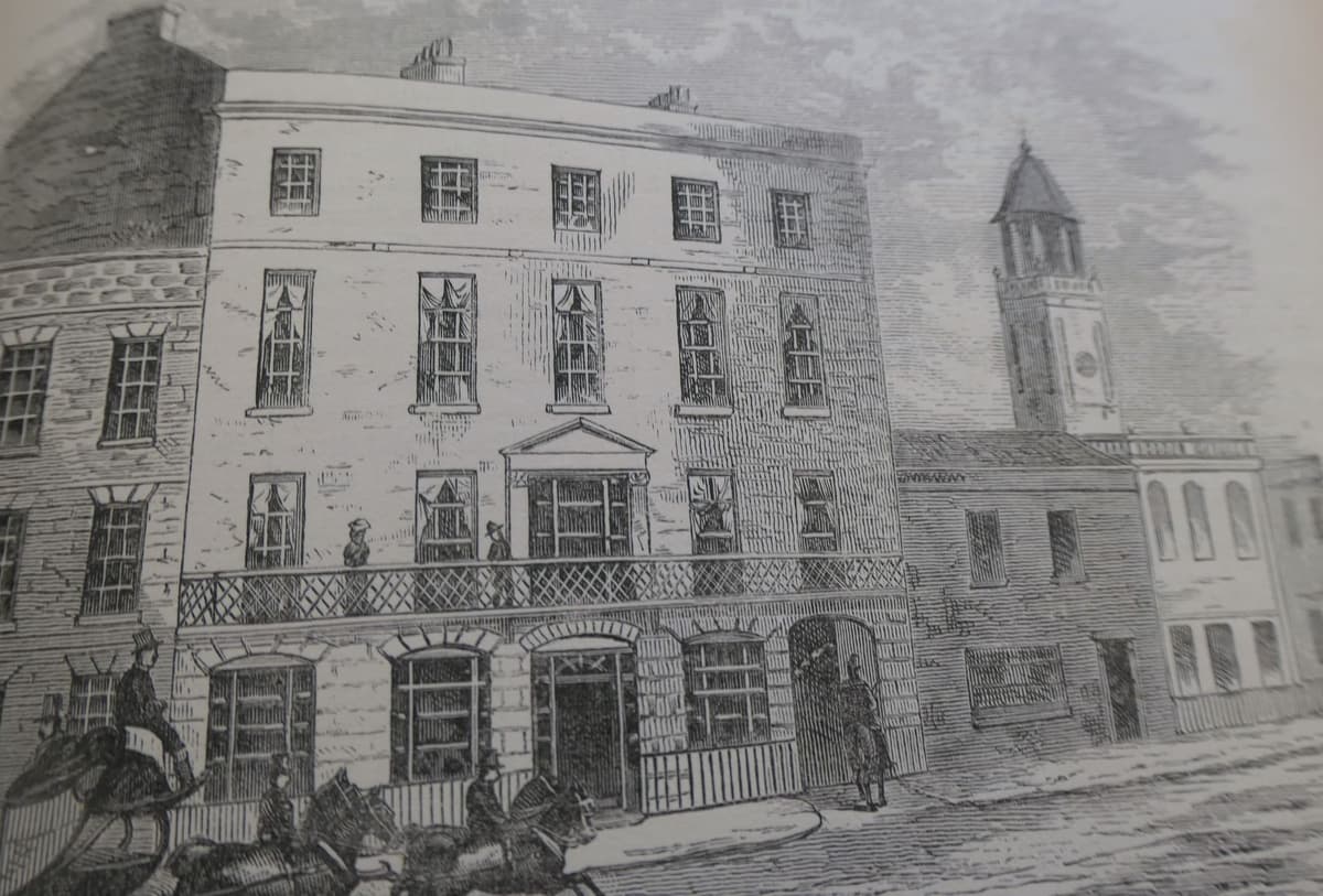 Victorian engraving of a hotel’s balconied front on a city street.