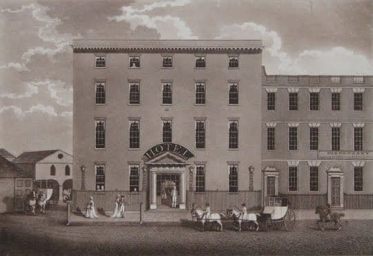Engraving of a tall, plain four-storey Georgian building with ‘HOTEL’ over its doorway and carriages in front.