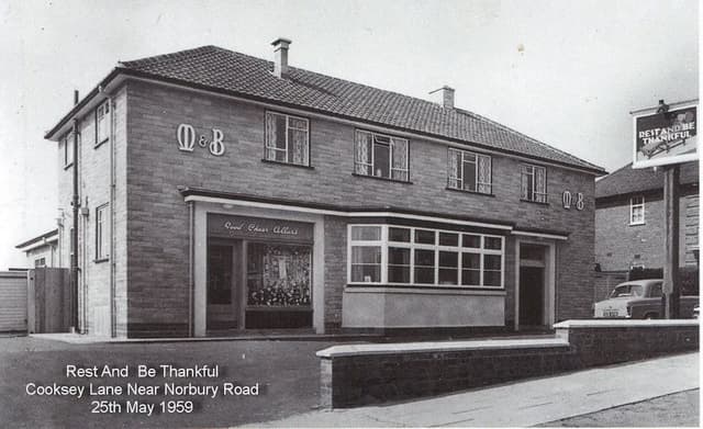 A new two-storey Mitchells & Butlers pub with M&B lettering, a Good Cheer Cellars off-licence window and a hanging sign reading Rest and Be Thankful