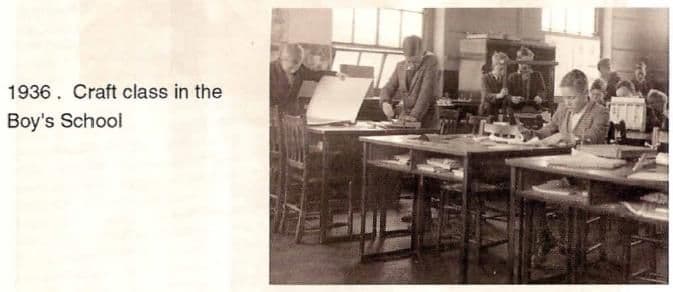 A scanned booklet page: boys working at wooden benches in a well-lit craft room. Printed beside it: “1936. Craft class in the Boy’s School”.