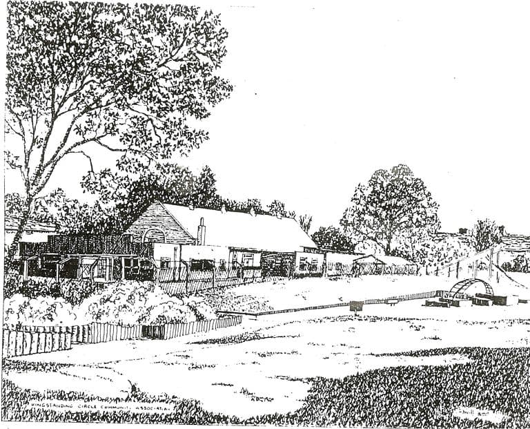 A black-and-white pen drawing of a long, low community building with flat-roofed extensions in front of an older gabled hall, behind a picket fence and a large tree, with an open grassy space and a small climbing arch in front. Lettering along the bottom reads “Kingstanding Circle Community Association”.
