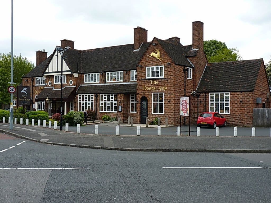 Brick and half-timbered inter-war pub with a leaping-deer sign on its gable, on a corner of Queslett Road