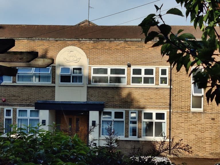 Close view of the Army Reserve Centre entrance: a white panel with a carved crest above a canopied doorway in a brick frontage.