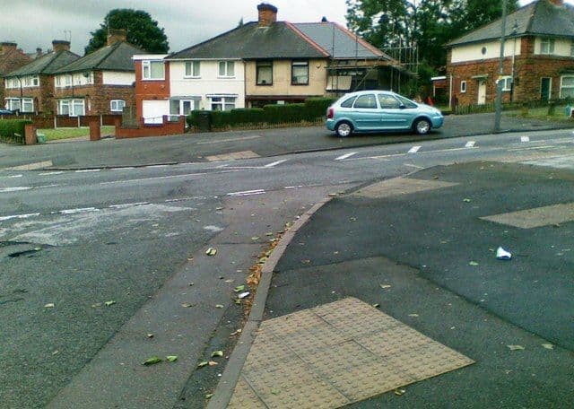 Houses on Danesbury Crescent seen across a road junction, with a parked car and a dropped kerb in the foreground.