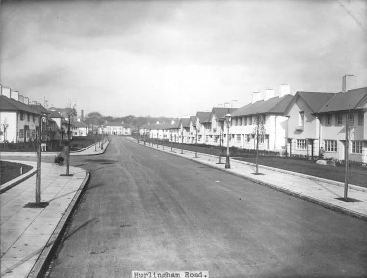 Hurlingham Road newly completed: a broad straight road with verges, young trees and white rendered houses receding into the distance.