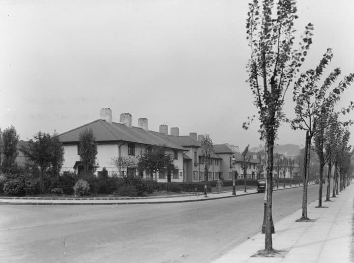 Hurlingham Road with a line of tall young trees along the footway and a hipped-roof terrace behind mature front gardens.