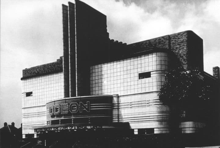 1935: The Odeon cinema when new: a streamlined tiled frontage with a tall fin tower and the name Odeon above the entrance.