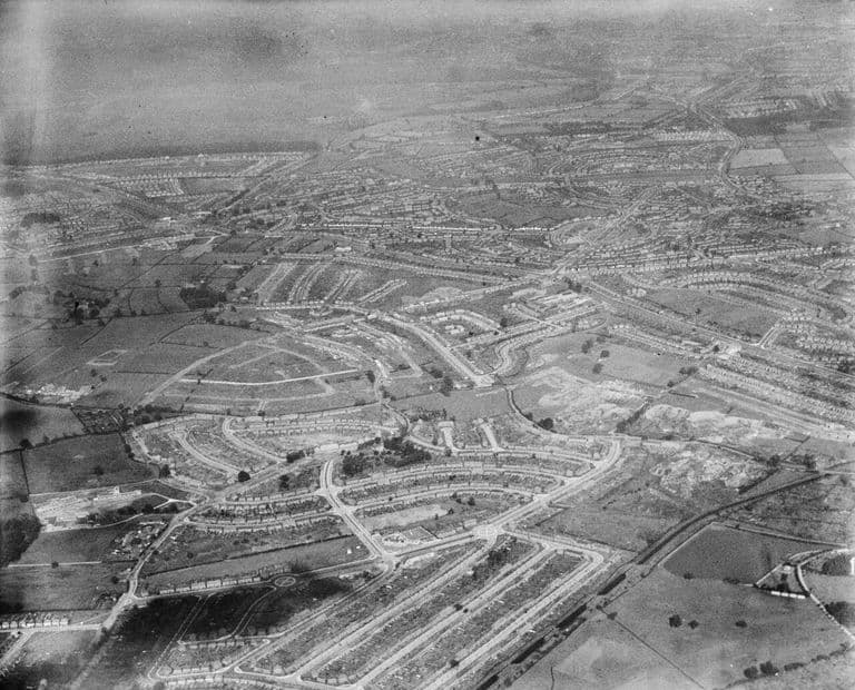 Oblique aerial photograph from the south-west: new crescents and building sites in the foreground and the wider estate beyond.