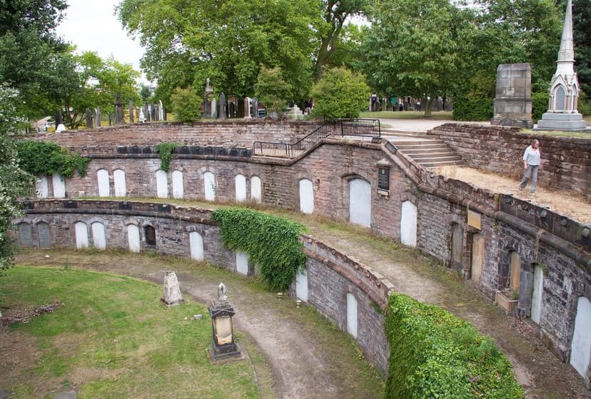 A curving terrace of sealed brick catacomb vaults set into a grassy bank.