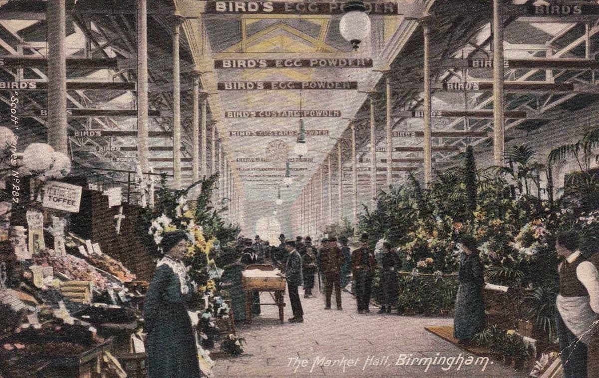 Postcard view of the interior of the Market Hall, with stalls and advertising.