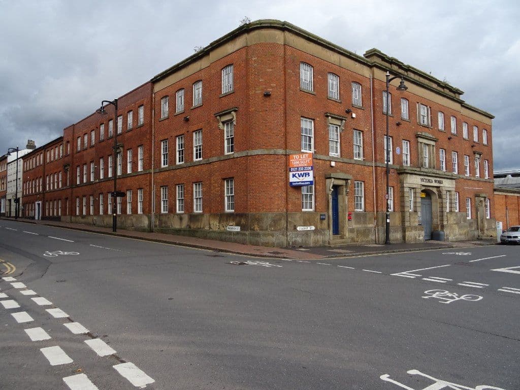 The three-storey red-brick front of Victoria Works with a central arched entrance.