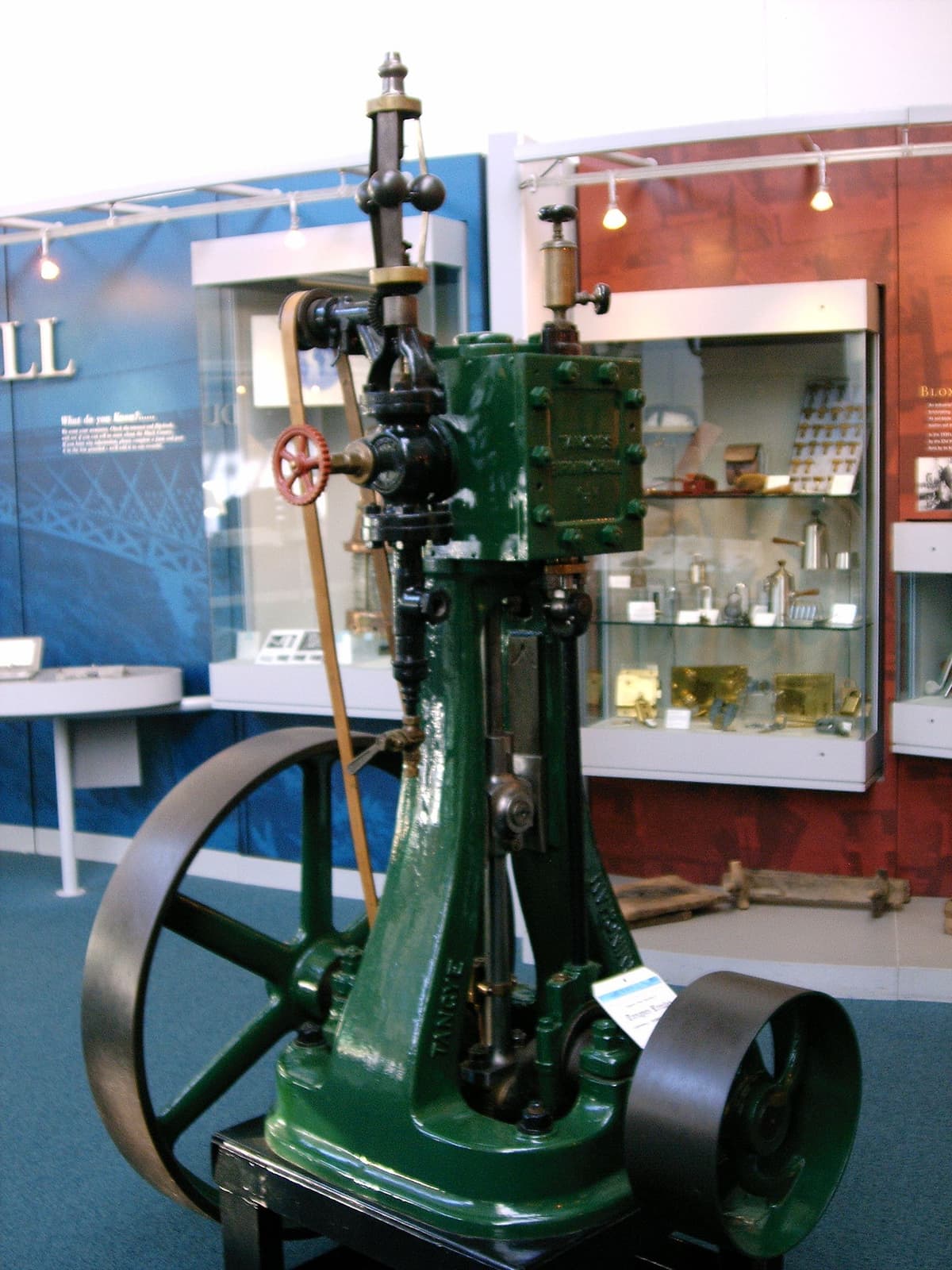 A small green Tangye steam engine on display in a museum.