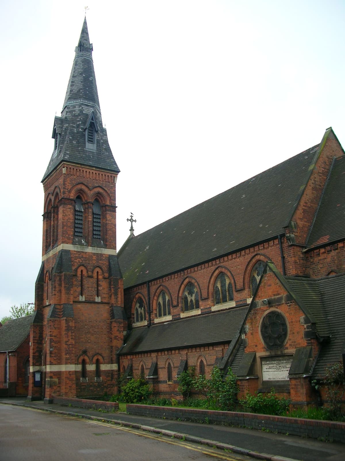 Red-brick Gothic church with a slate broach spire.