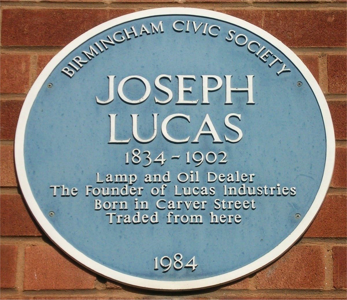 Round blue Birmingham Civic Society plaque reading Joseph Lucas 1834–1902, Lamp and Oil Dealer, The Founder of Lucas Industries, Born in Carver Street, Traded from here, 1984.