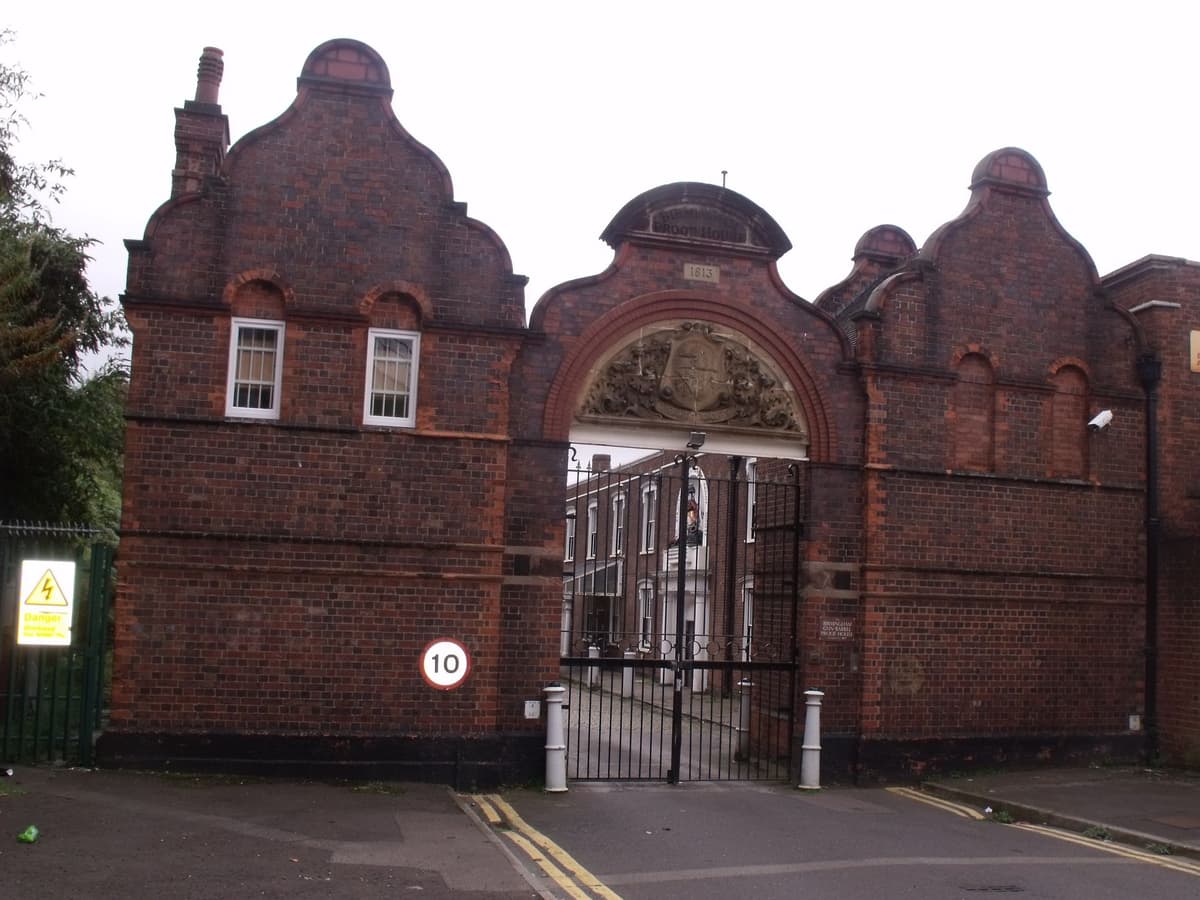 A red-brick building with a shaped gable and a large round-arched gateway.