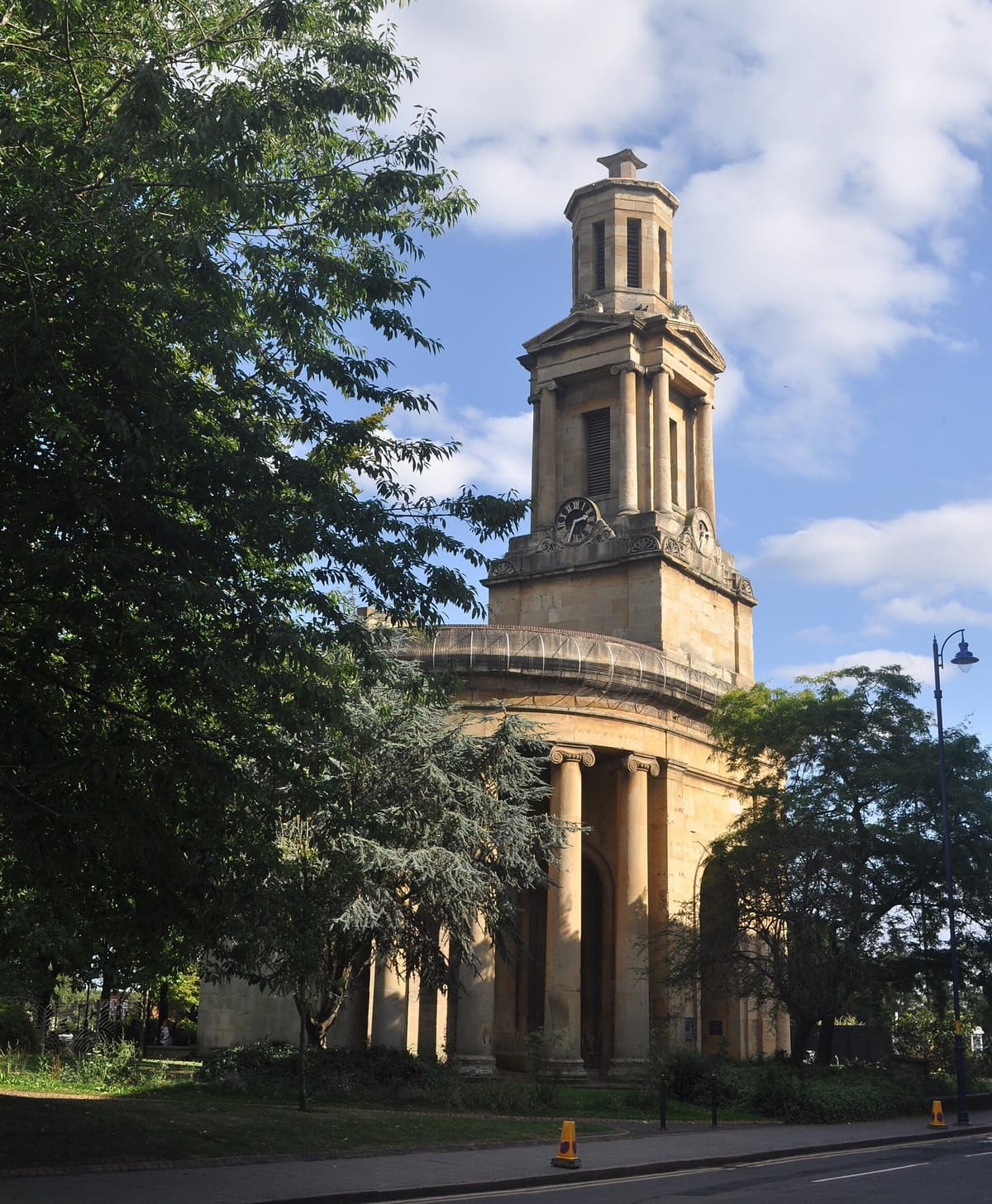 Classical stone church front and tower standing alone in a garden.
