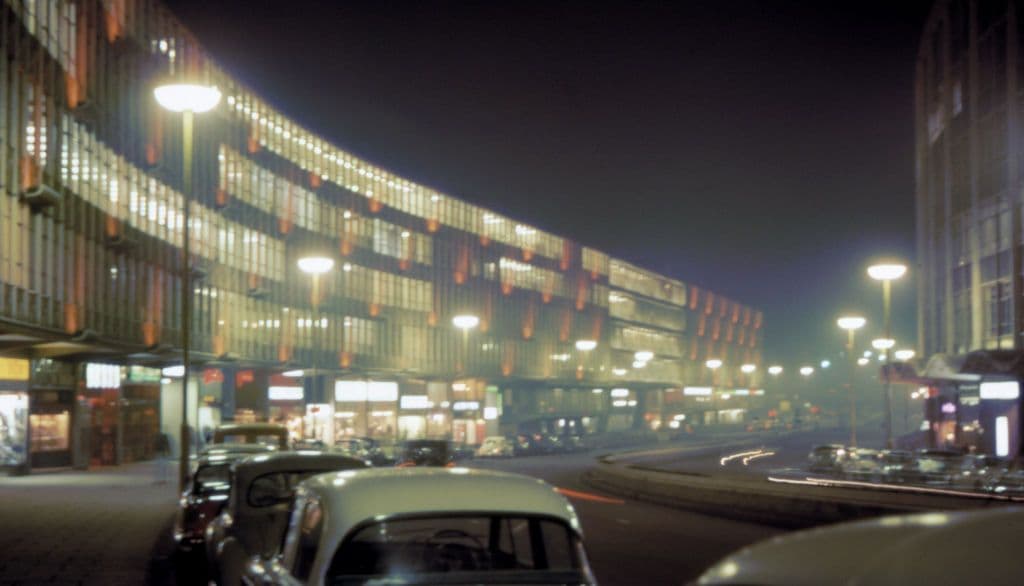Night photograph of a lit modern street with car headlights.