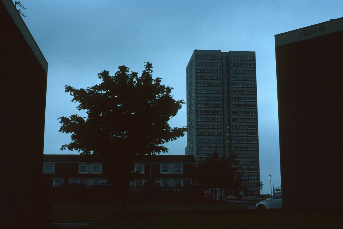 Tall council tower blocks seen across open ground.