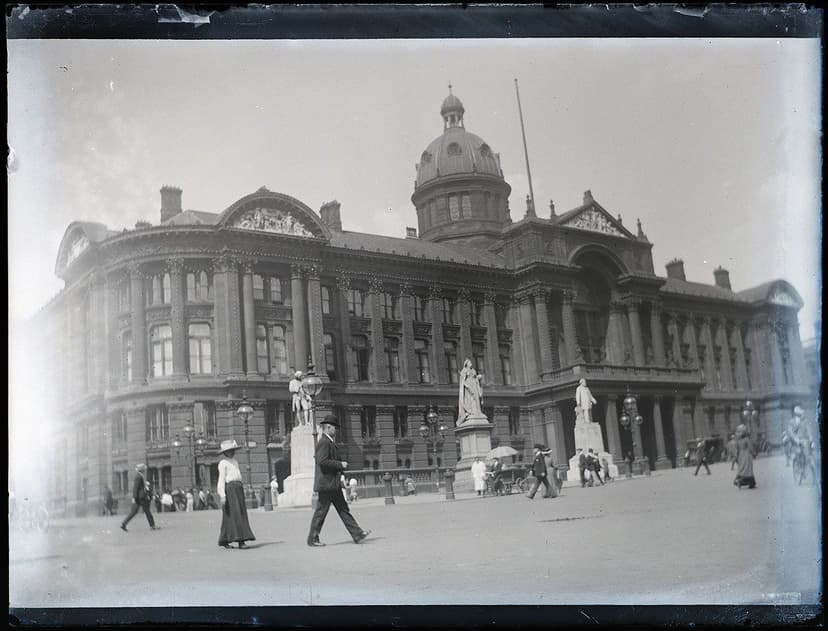 An early photograph of a domed civic building with horse-drawn traffic in front.