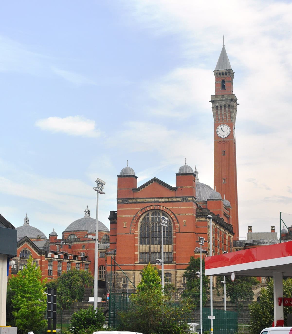 A domed red-brick university hall with a tall brick clock tower rising behind it.