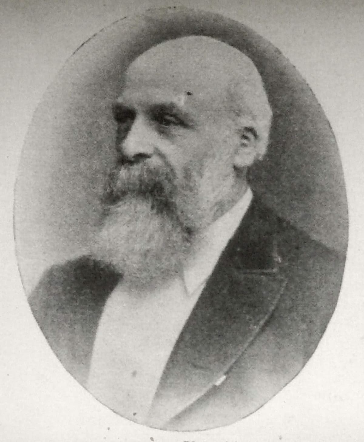 Oval photographic portrait of a balding Victorian man with a long white beard, in a dark coat, looking to the left.