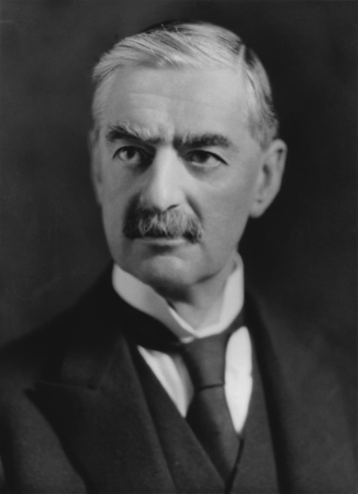 Black and white studio portrait of a man with greying hair, heavy eyebrows and a moustache, in a dark suit and wing collar, looking straight at the camera.