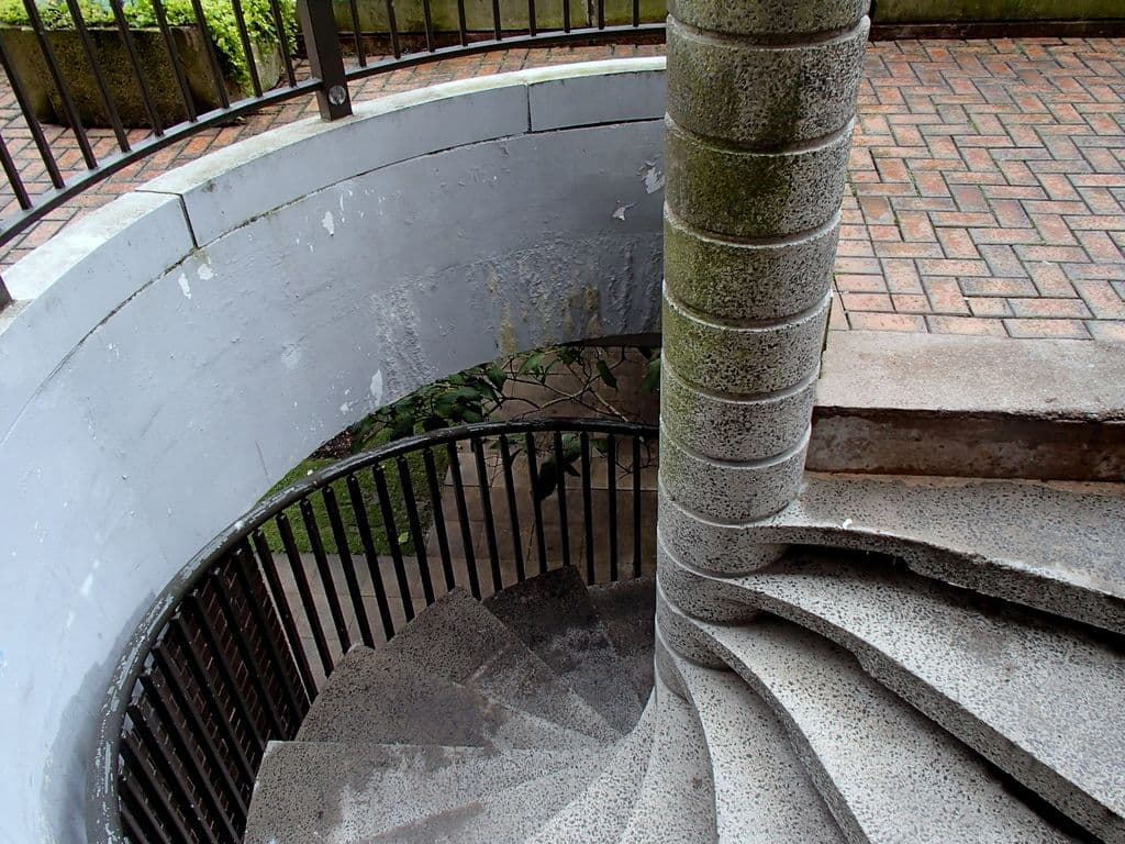 A concrete spiral staircase leading down to a road level.
