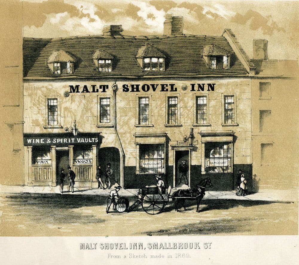 Engraving of a low old inn with a sign, between taller buildings on a town street.