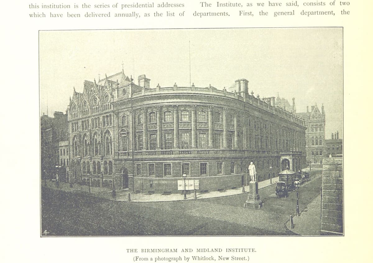 Photograph of a three-storey Renaissance building with a rounded corner, a statue in the street before it and a Gothic wing beyond.