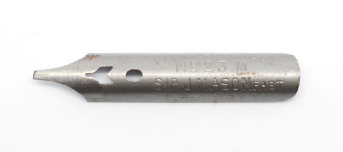 Close-up of a single steel pen nib stamped No. 23 M and Sir J. Mason.