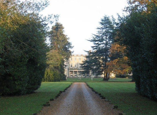 A large plain eighteenth-century country house in parkland.