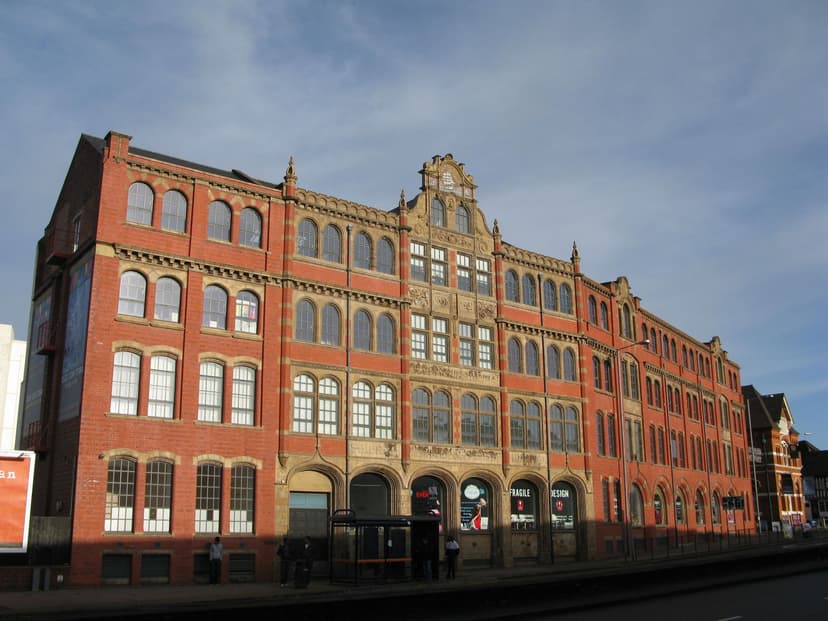 A four-storey red brick and terracotta factory front with arched windows and a shaped gable.