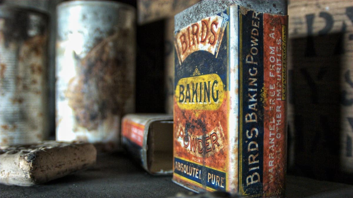 Old rusted tins on a shelf, one a packet of Bird’s Baking Powder.