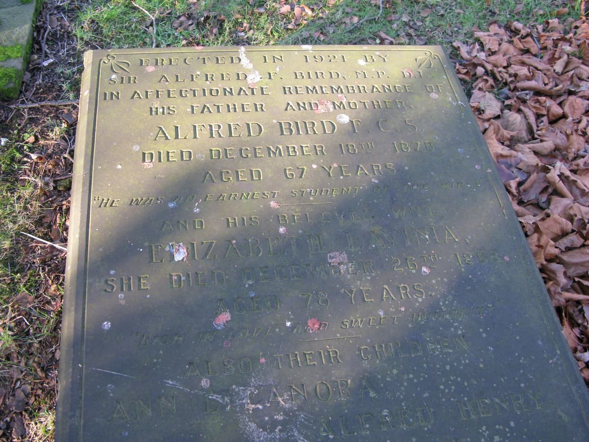 A flat inscribed gravestone lying in grass.