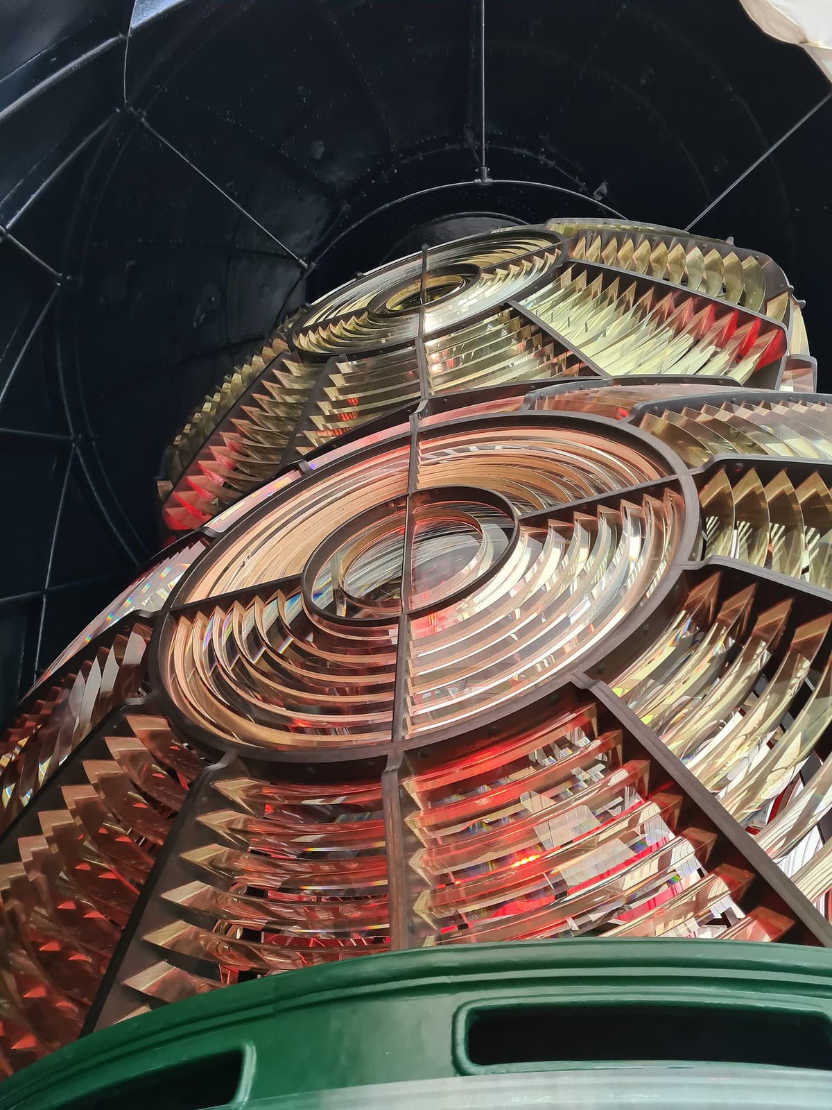 Close view of a large lighthouse lens made of rings of glass prisms in a metal frame.