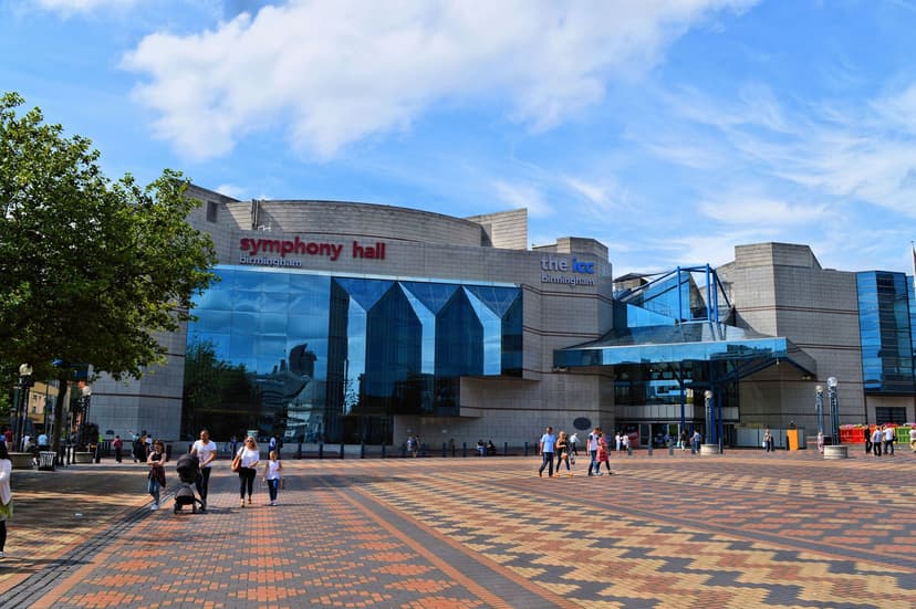 A large modern convention centre and concert hall at the end of a paved square.