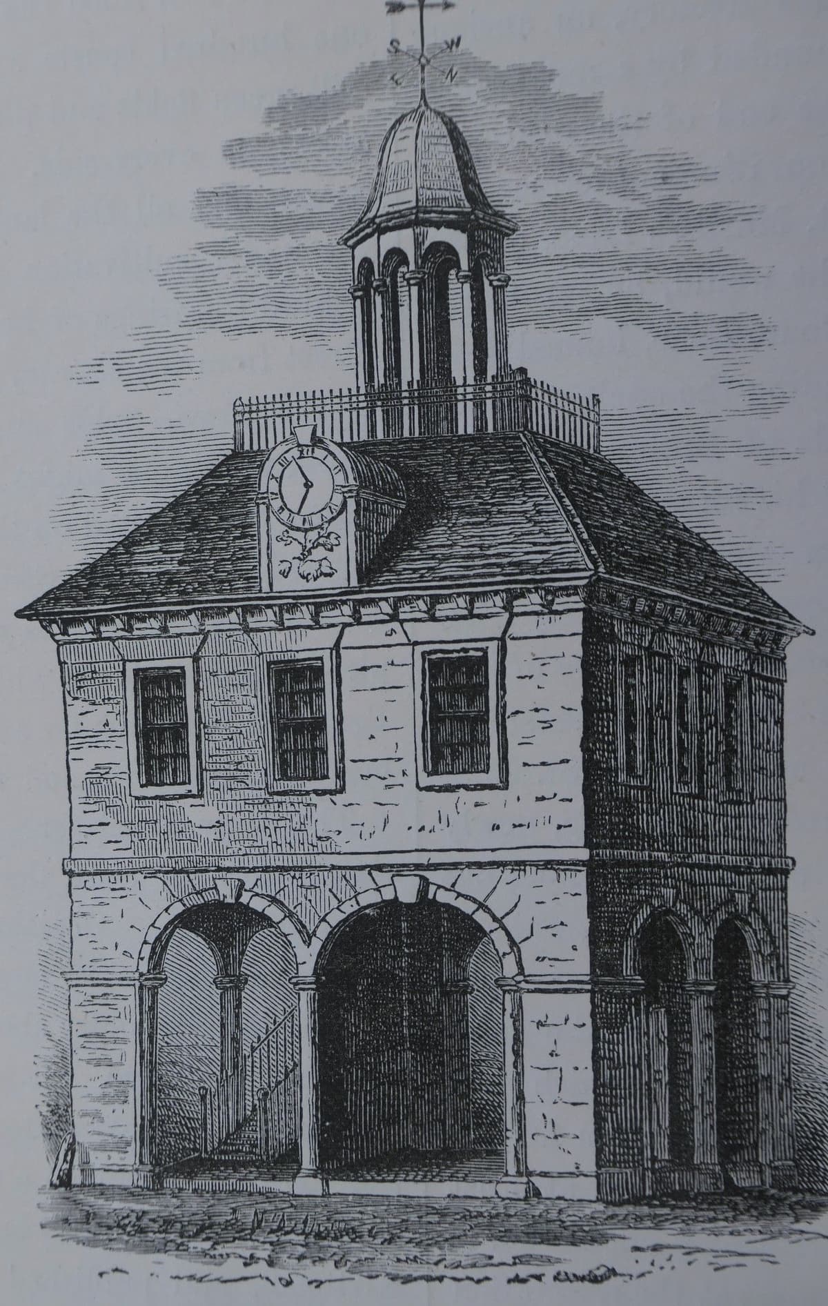 Engraving of a small square two-storey market house with open arches below, sash windows above, a hipped roof, a clock and a cupola.