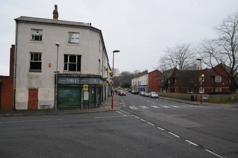A run-down brick industrial building on a city street.