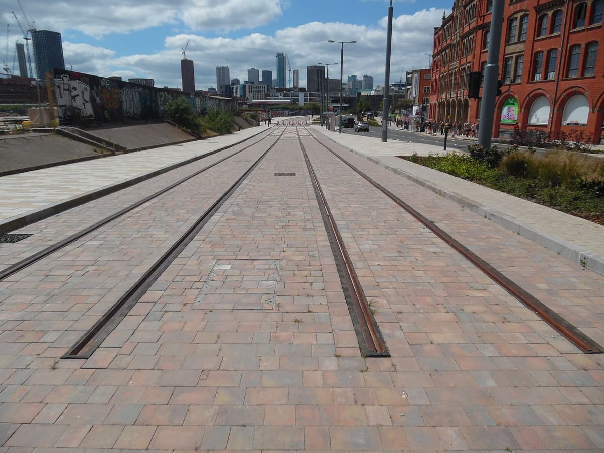A wide city street with new tram tracks set in the road.