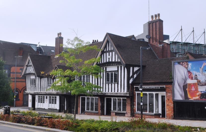 A black-and-white timber-framed pub with two gables and a jettied upper floor on a city street.
