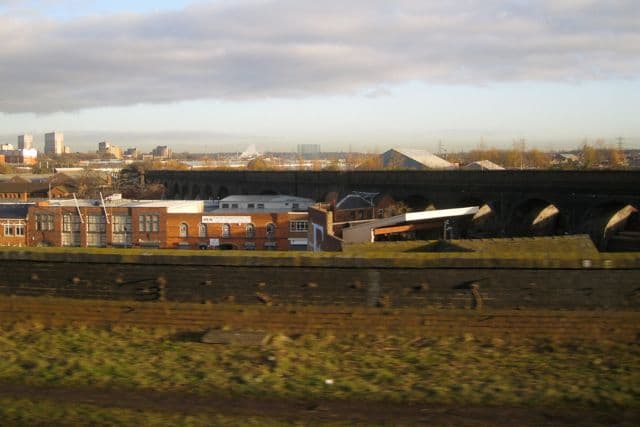 A disused brick viaduct crossing industrial premises.