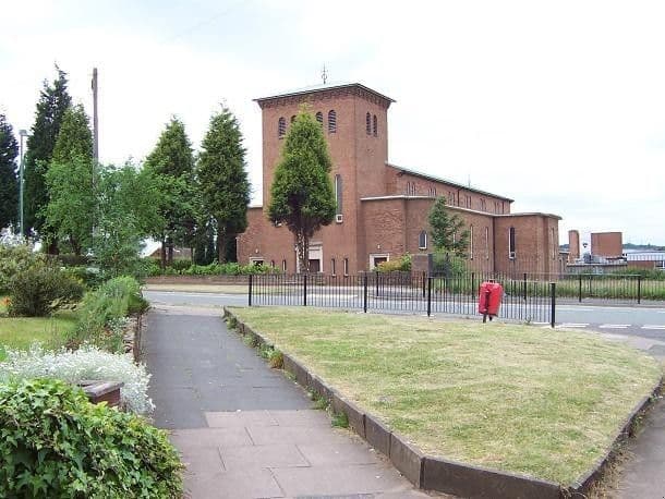 Brick Catholic church with a tall square tower behind a railing, grass and a footpath, beside the road at Old Oscott Hill