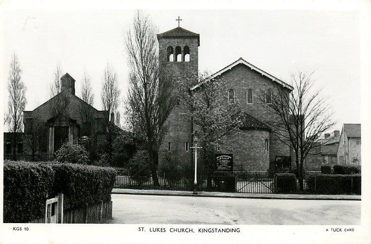 Black-and-white postcard of St Luke’s Church, Kingstanding, around 1950: a brick church with a tall bell tower behind hedges and railings