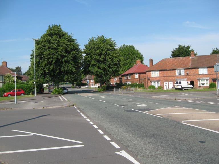 Witton Lodge Road at its junction with Dovedale Road in July 2014, with red-brick estate houses and large trees