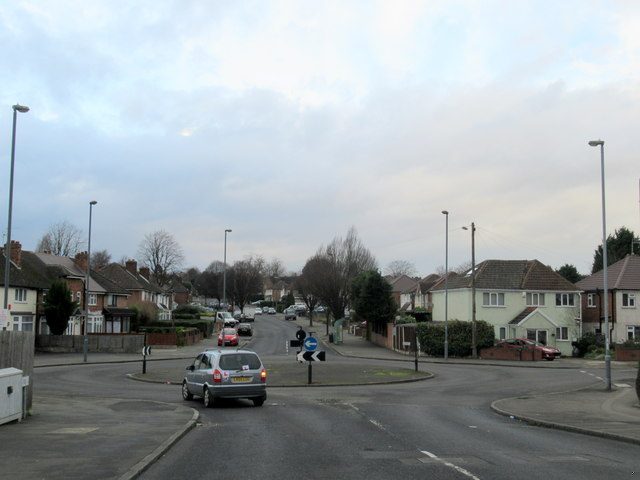 A small traffic island at a road junction lined with semi-detached houses